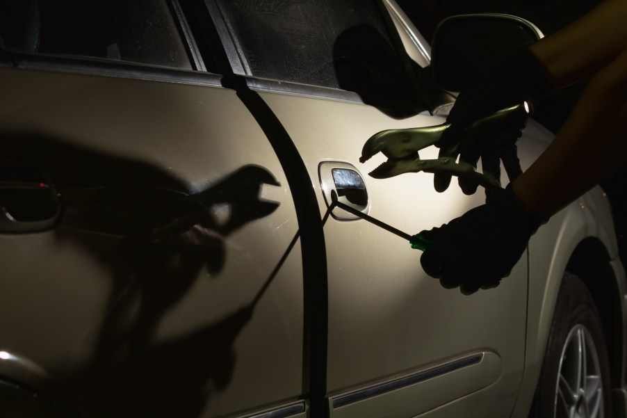 A thief using tools to break into a truck