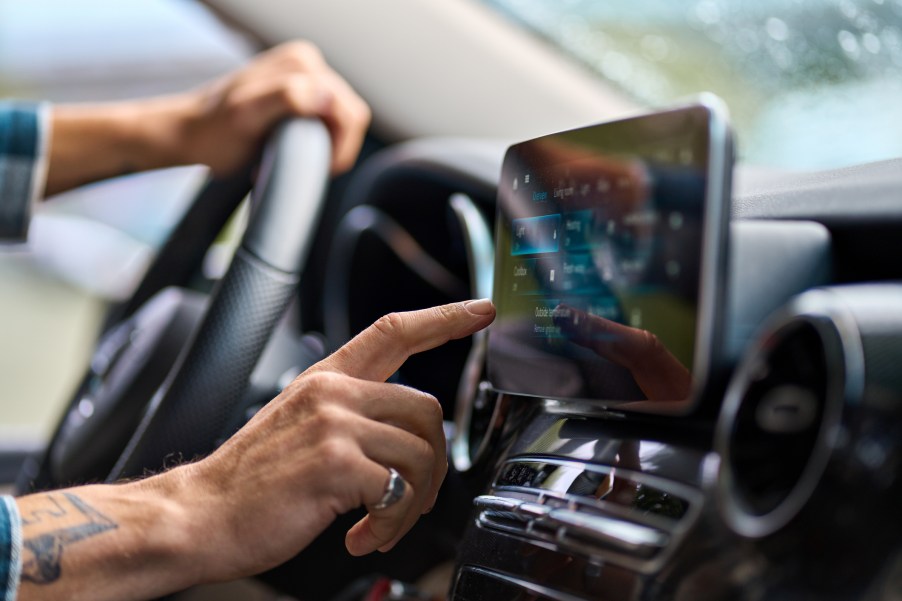 A man using a touchscreen is a car