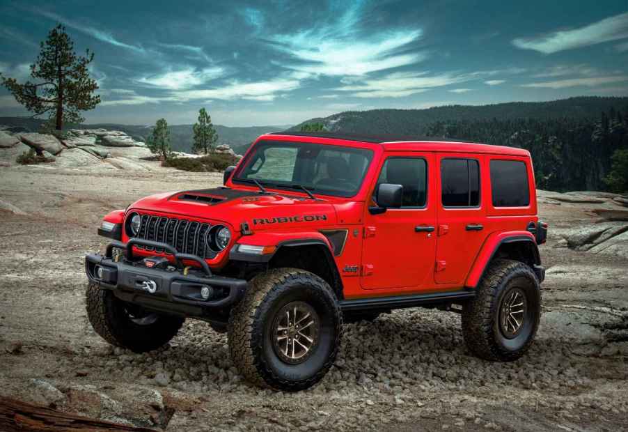 A red Jeep Wrangler Rubicon sits on a gravel road of a mountain