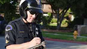 Police officer standing writing a traffic ticket citation wearing a motorcycle helmet
