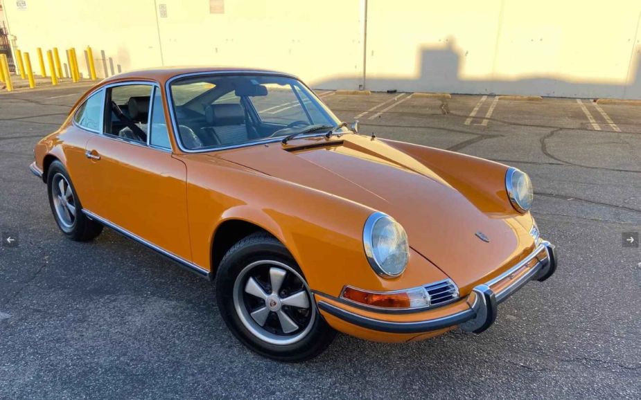A classic orange Porsche sits in a parking lot before being sold at auction