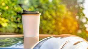 A pumpkin spice latte cup on a car roof in close view