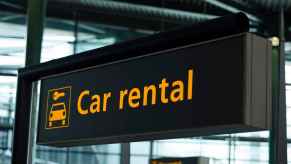 Rental car sign handing from the wall at an airport in close view
