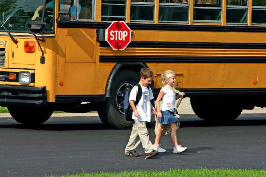 Children getting off of a school bus and crossing the street