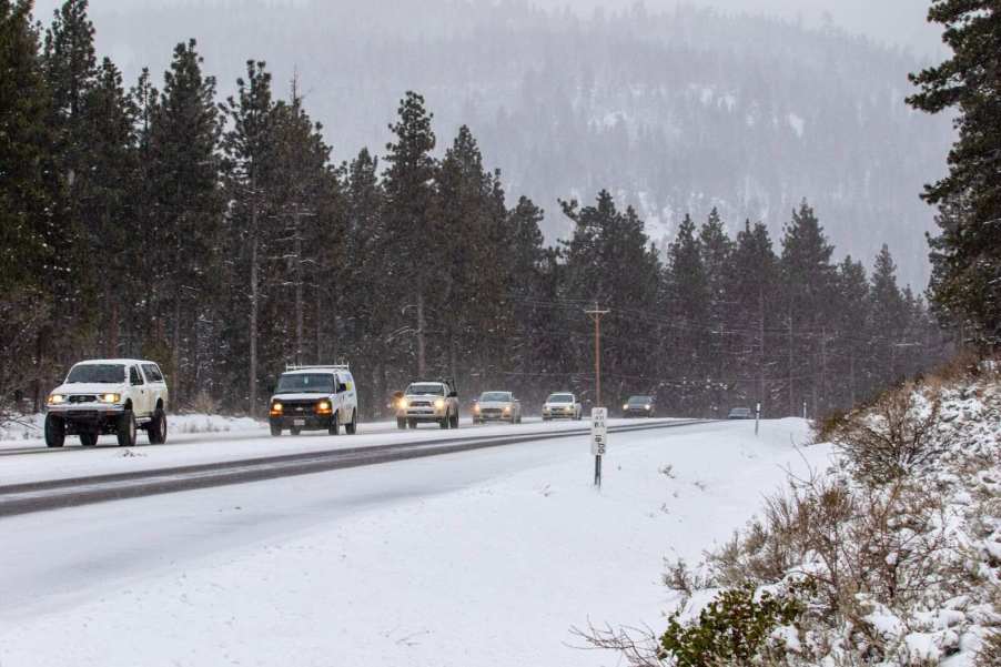 Cars driving on a snowy mountain highway during snowfall