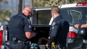 Two California police officers perform a vehicle search inspecting contents on a pickup truck bed