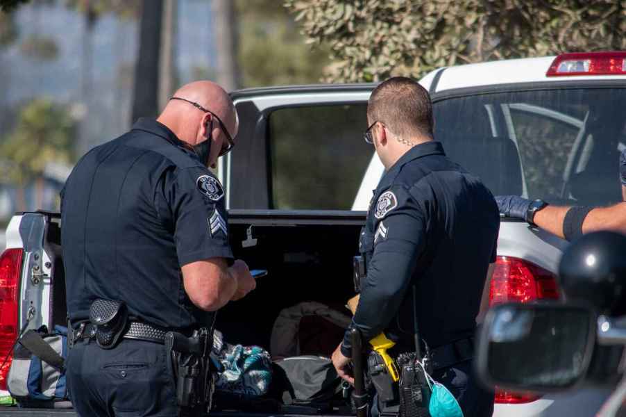 Two California police officers perform a vehicle search inspecting contents on a pickup truck bed