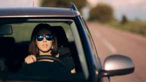 A woman driver pulled over facing viewer with worried look on face perhaps during police traffic stop