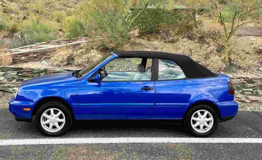 A bright blue 1998 VW Cabrio two-door convertible parked outside in full left profile view