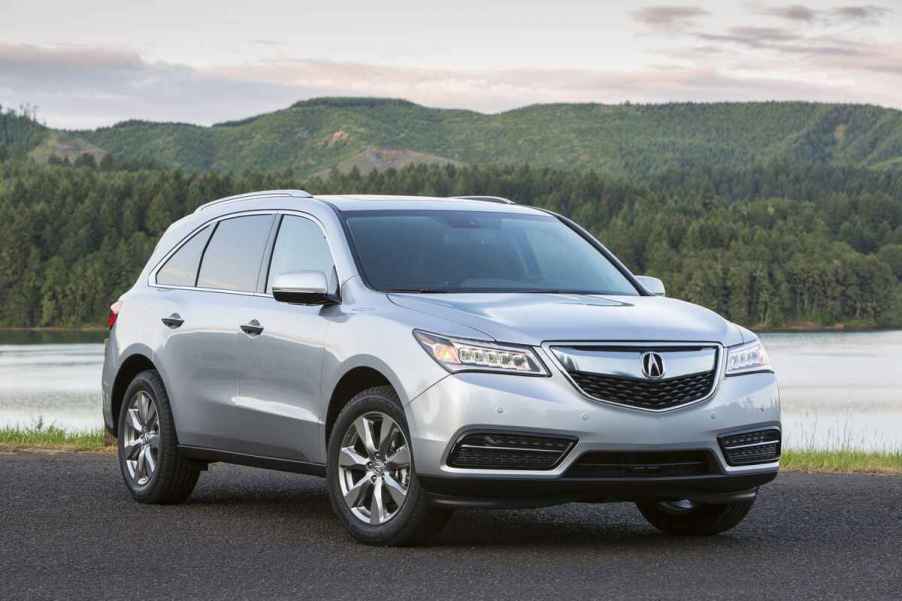 A silver 2015 Acura MDX parked in front of water and a mountain in right front angle view