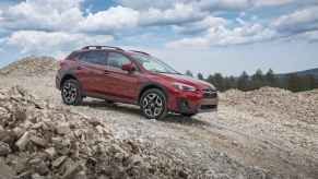 A dark red 2019 Subaru Crosstrek parked on a rocky slope in right side angle view