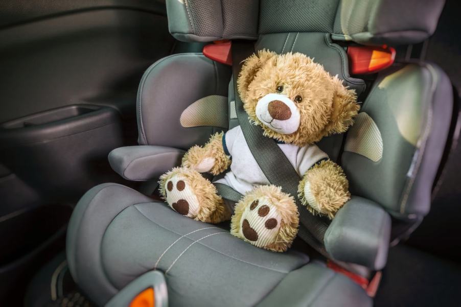 A car seat holds a teddy bear for a baby.