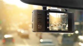 View of a street through a dashcam hung from a windshield.