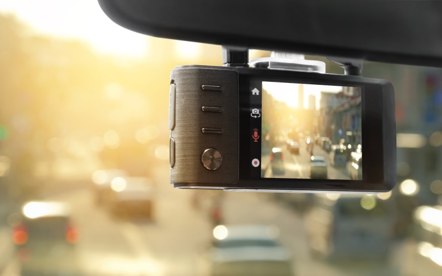 View of a street through a dashcam hung from a windshield.