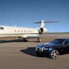 Black Rolls Royce coupe parked on a taxiway, a gulfstream jet in the background.