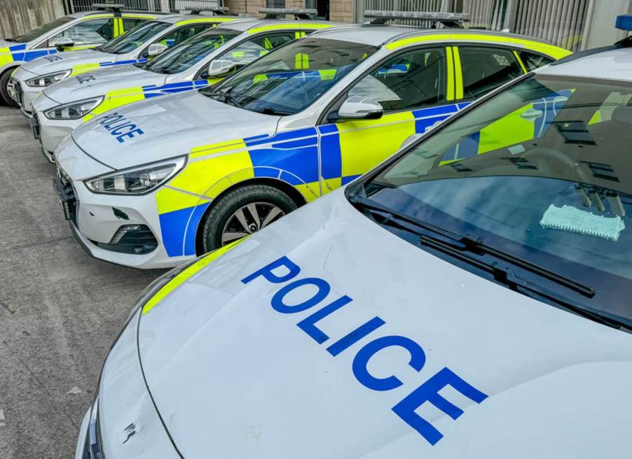 A row of yellow and blue UK police cars in Bath.