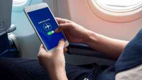 An airplane passenger putting a cell phone on airplane mode inside plane cabin