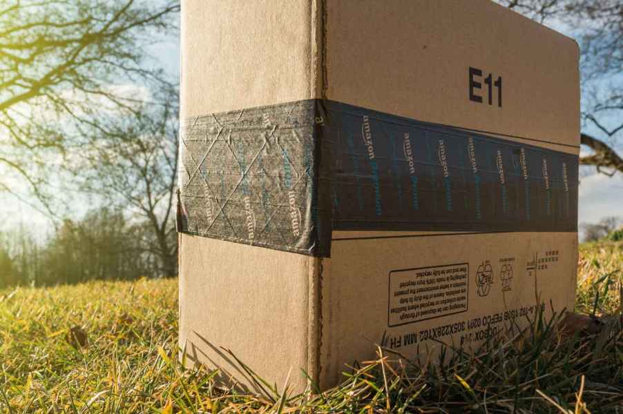 An Amazon package sitting in the sunlight on a bed of grass