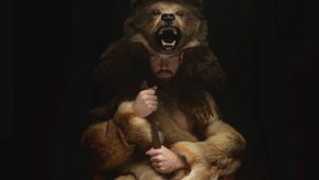 Man wearing a realistic bear costume while looking menacingly at the camera