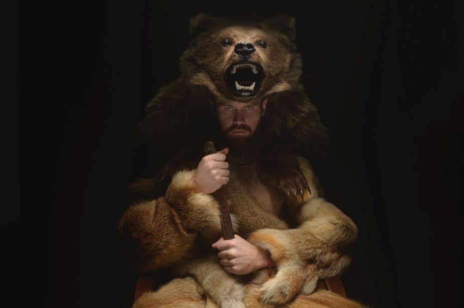Man wearing a realistic bear costume while looking menacingly at the camera