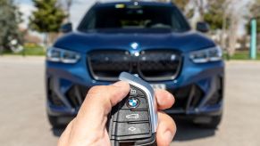 A person holding the key fob to a BMW SUV