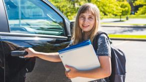A young girl getting into a car to go to school