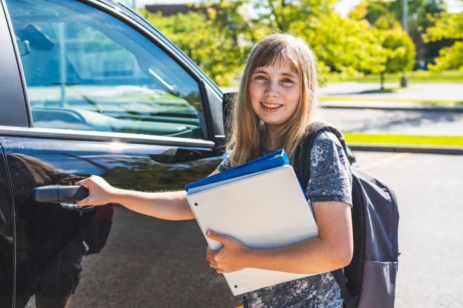 A young girl getting into a car to go to school
