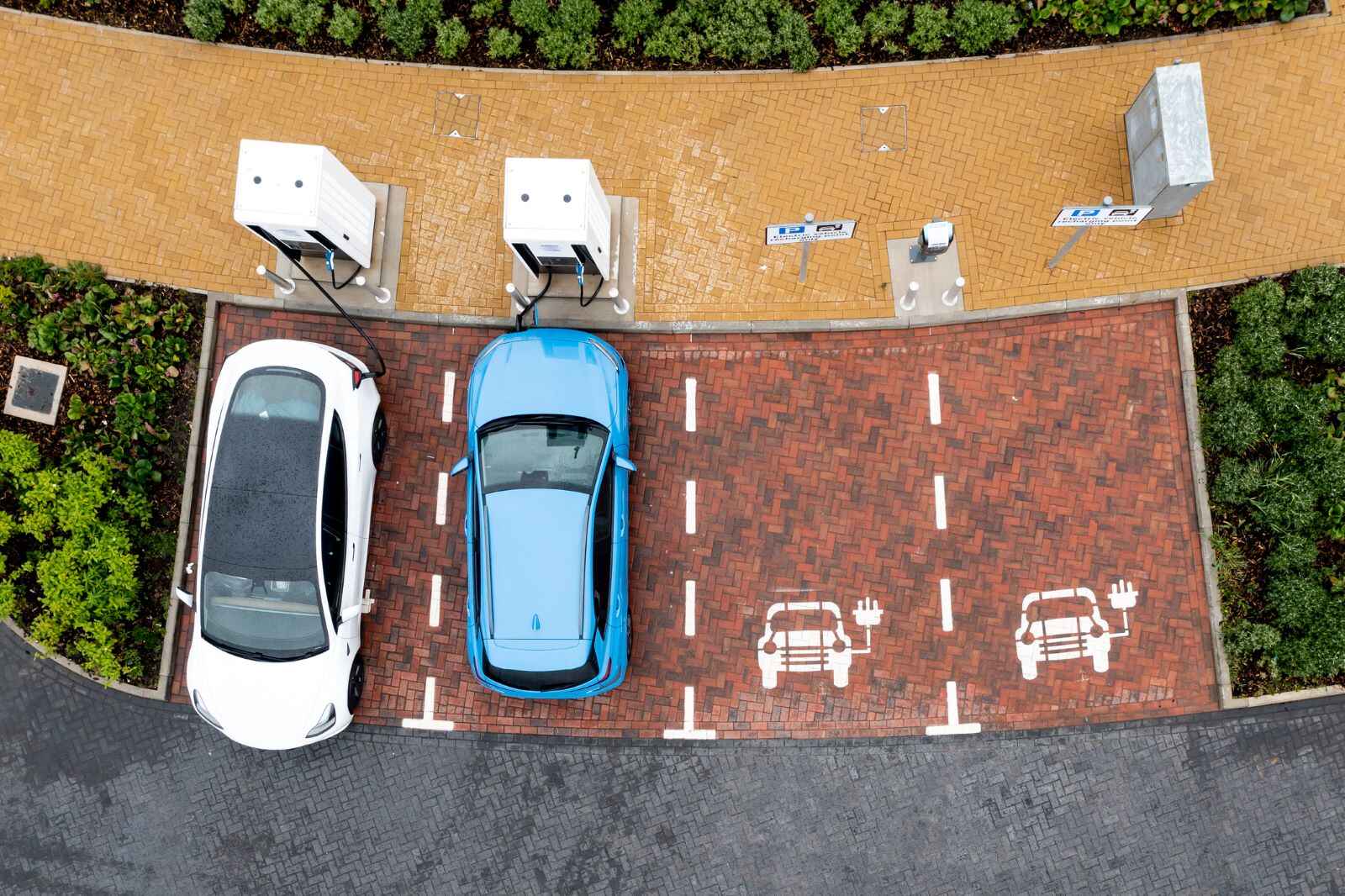 Electric vehicles charging at a charging station, with two EVs parked and charging while two spots remain empty