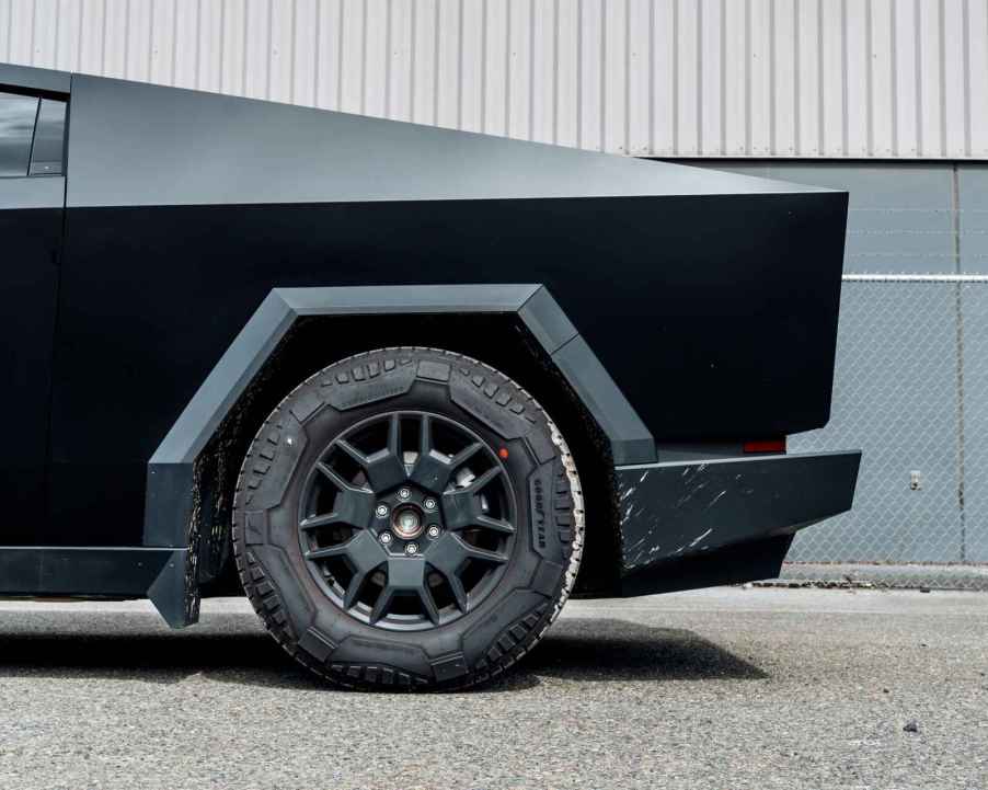 The rear quarter panel of a matte black Tesla Cybertruck