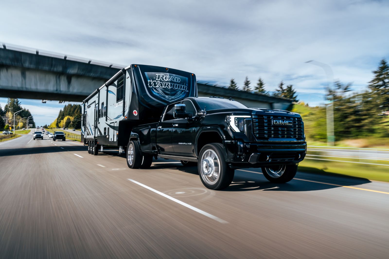 A 2024 GMC Sierra HD Denali truck pulling a fifth wheel trailer on a busy highway