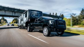 A 2024 GMC Sierra HD Denali truck pulling a fifth wheel trailer on a busy highway