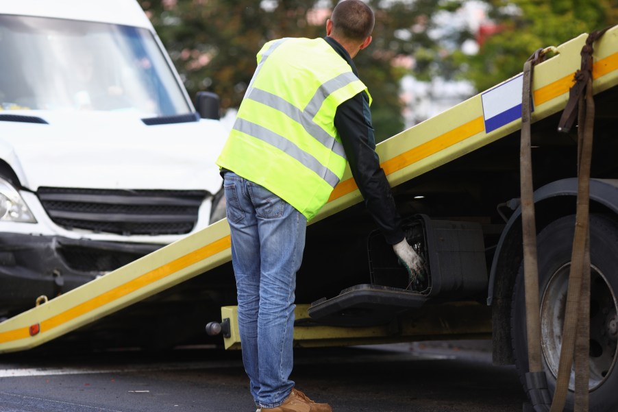 A man loading a van onto a tow truck