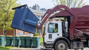 A garbage truck picking up a dumpster