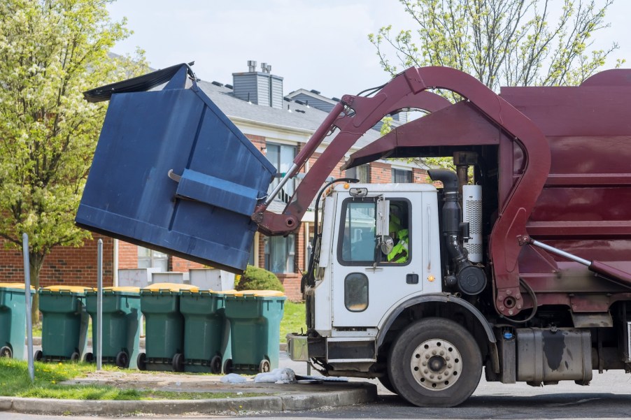 A garbage truck picking up a dumpster