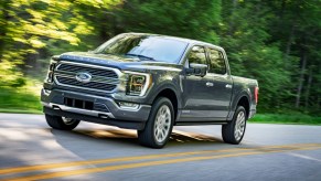 A 2021 Ford F-150 driving on a two-lane road in left front angle view