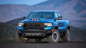 A blue 2024 Ram 1500 parked in front of a mountain at dusk in left front angle view