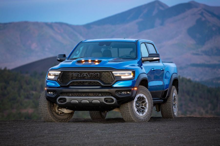 A blue 2024 Ram 1500 parked in front of a mountain at dusk in left front angle view