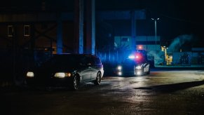 A drunk driving arrest in progress with a police officer and a Volvo wagon.