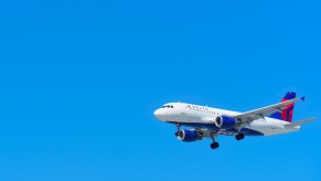 Delta airlines jet plane in a bright blue sky.