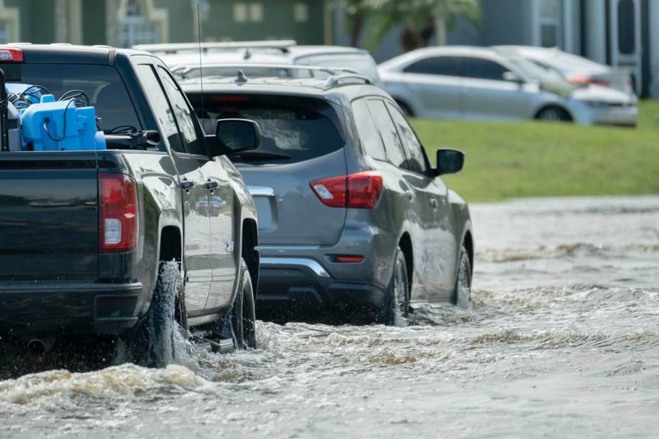 A series of cars battle flooding with high waters on the road.