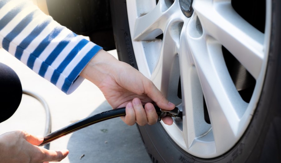 Driver inflates her tires using an air compressor at a gas station