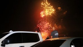 A car and an SUV are near fireworks, which can light a car on fire in seconds if participants aren't careful.