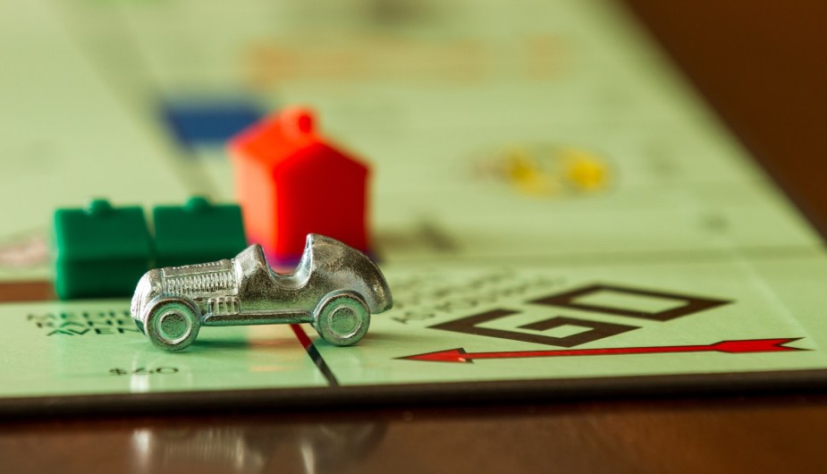 Monopoly board game set up with a game piece and houses.
