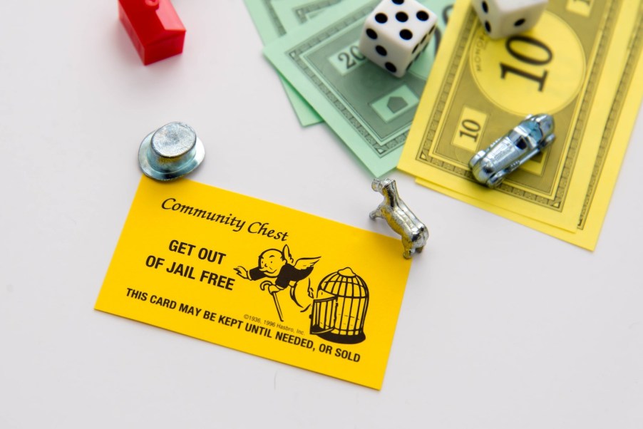 Bright yellow monopoly car in front of monopoly tokens and money