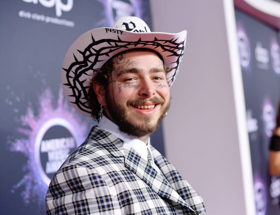 Musician Post Malone at an award show, wearing a cowboy hat on state.