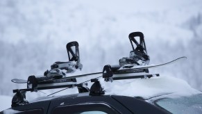 Snowboard locked to rental car in front of a ski mountain.