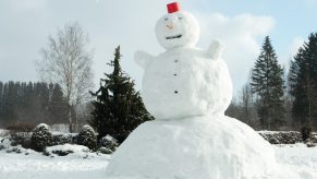 A large snowman in an empty field.