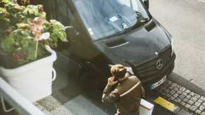 Overhead view of a UPS driver delivering a package, his truck visible in the background