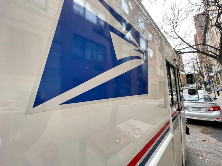 A USPS mail truck on a city street.