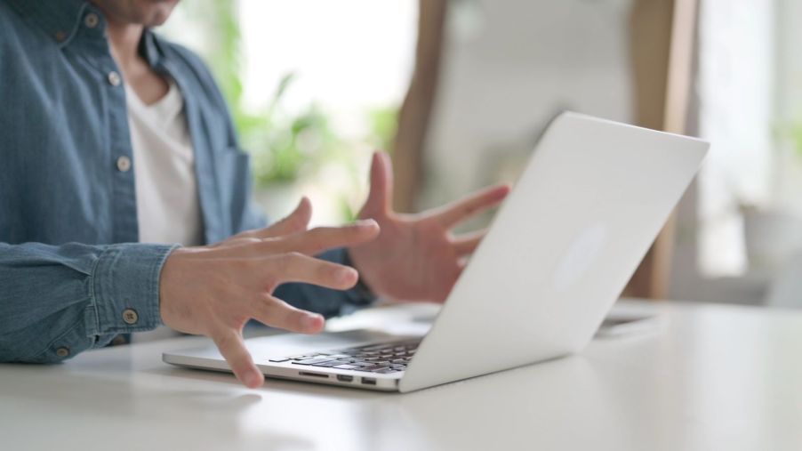 A man writing an angry email, expressing frustration with his hands